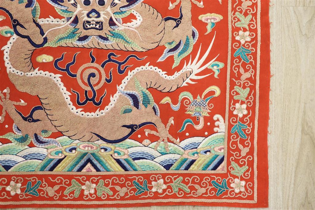 A early 20th century Chinese red felt square panel embroidered with a central motif of a dragon, width 86cm height 84cm